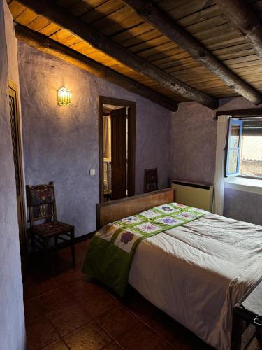 a bedroom with a bed and a chair and a window at Alma de Villuercas CR-CC-0070 in Cabañas del Castillo