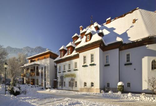 a large white building with snow on the ground at Wohlfühlhotel Goiserer Mühle in Bad Goisern