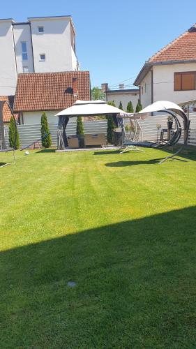 a lawn with two umbrellas in a yard at Comfort Inn Apartmani in Vrnjačka Banja