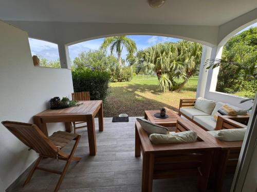 a porch with a couch and a table and chairs at Charmant en bord de plage in Anse Marcel 