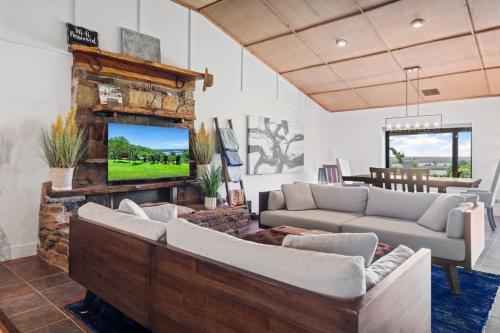 a living room with two couches and a flat screen tv at Twisted Tree with Arkansas River Views and Hot Tub in Muskogee