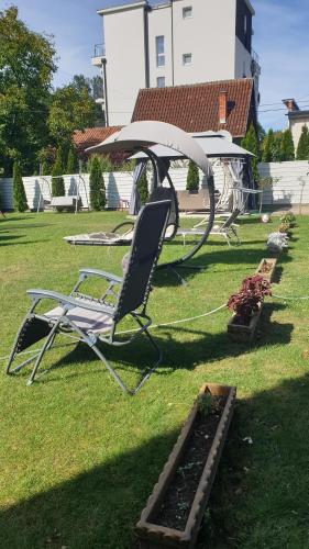 a chair sitting under an umbrella in a yard at Comfort Inn Apartmani in Vrnjačka Banja