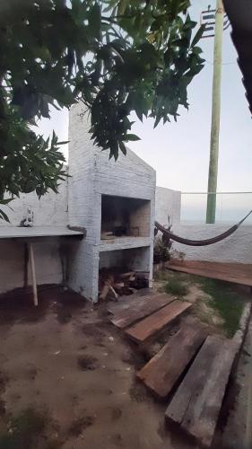 a brick fireplace sitting in a yard with a bench at Casa a beira-mar in Santa Vitória do Palmar