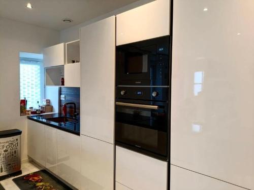 a kitchen with white cabinets and a black oven at LOasis Dijonnaise 8 PEOPLE in Sennecey-lès-Dijon