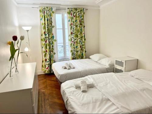 une chambre avec deux lits et une table et une fenêtre dans l'établissement Haussmannien de Luxe, à Paris