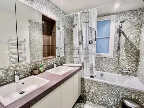 La salle de bains est pourvue de 2 lavabos, d'une baignoire et d'une fenêtre. dans l'établissement Haussmannien de Luxe, à Paris