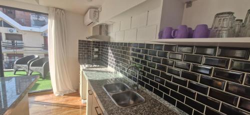 a kitchen with black and white tile on the wall at Vivisierras, Duplex a estrenar con pileta privada centro Villa Carlos Paz, 3 dormitorios, 2 baños, vista in Villa Carlos Paz