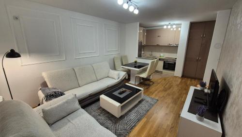 a living room with a white couch and a kitchen at Premium Bel in Donje Mladice