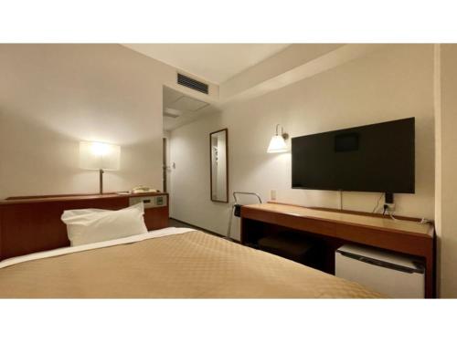 a hotel room with a bed and a desk with a flat screen tv at Kusatsu Daiichi Hotel - Vacation STAY 99284v in Kusatsu