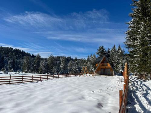 eine Holzhütte im Schnee mit einem Zaun in der Unterkunft Vikendica Monte Pino Romanija in Sokolac
