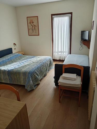 a bedroom with two beds and a chair and a window at Hotel Bel Sit in Madesimo