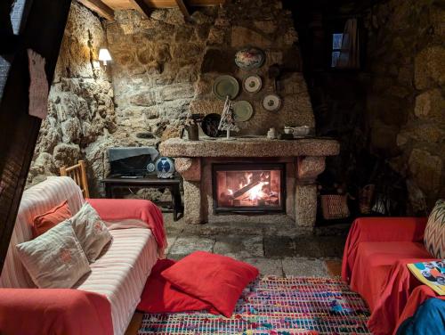 a living room with a stone fireplace and red couches at Casa das 5 Cruzes dentro da muralha in Sortelha