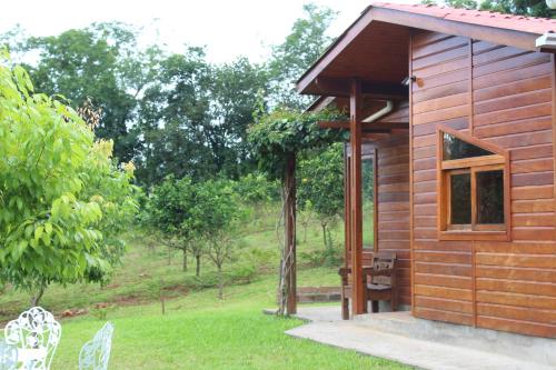 a wooden cabin with a window and chairs in the grass at Pousada Vila Felicita in São Valentim