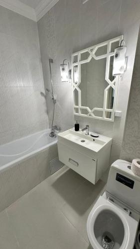 une salle de bain blanche avec un lavabo et des toilettes dans l'établissement Apartment, à Aqtöbe