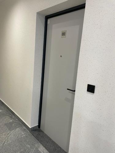 a white door with a sign on it next to a wall at Moaline Apartments, free parking in Sarajevo