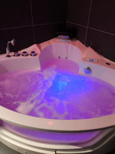 La salle de bains est pourvue d'une baignoire remplie d'eau violette. dans l'établissement Le spa des canuts, à Caluire-et-Cuire