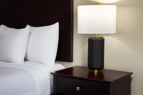 a lamp on a night stand next to a bed at Wyndham Tucson Airport Hotel & Conference Center in Tucson