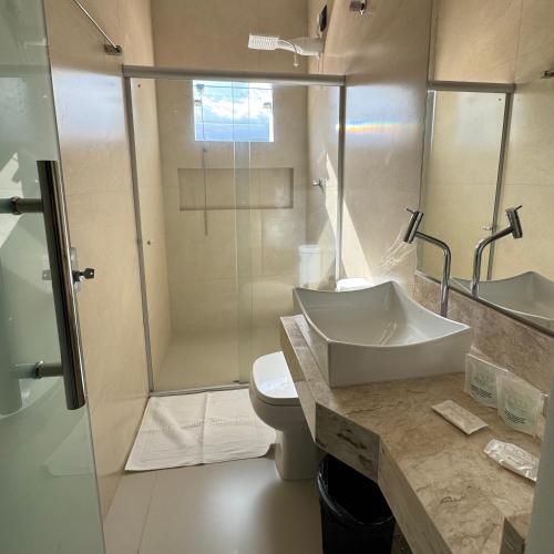 a bathroom with a sink and a shower and a toilet at Pousada Brumado in Brumado