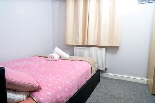 a bedroom with a pink bed with a pink doll on it at Greatmindz's home away from home in Bloxwich