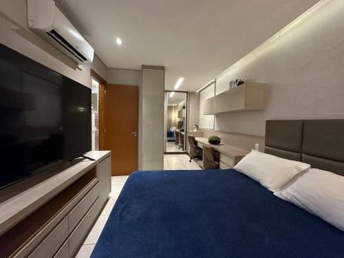 a bedroom with a blue bed and a flat screen tv at iFlat Winner Sport Life Jardim Goiás in Goiânia