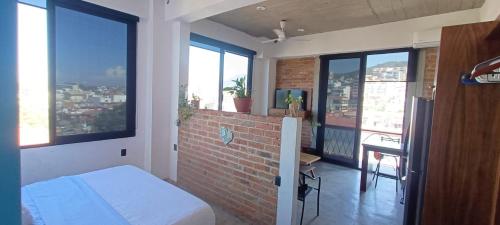 um quarto com uma cama, uma parede de tijolos e janelas em Luxo Studio Facing the Sea em Puerto Vallarta
