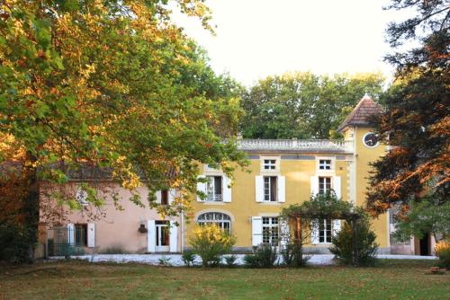 una gran casa amarilla con árboles delante de ella en Château de la Prade, en Bram