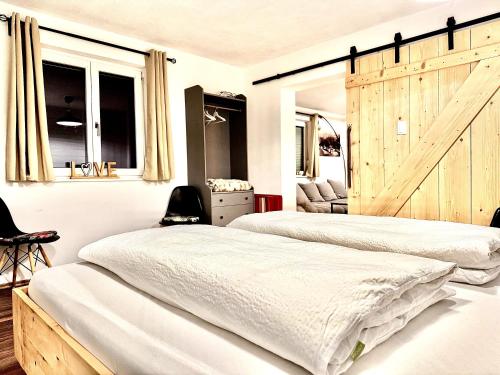 two beds in a bedroom with a sliding barn door at Sweet Home Apartments in Tösens