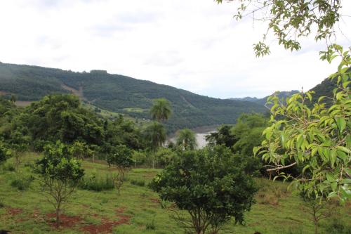 a field with trees and a river in the distance at Pousada Vila Felicita in São Valentim