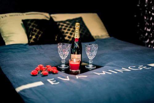 a bottle of wine and two glasses on a bed at Apartament American Express Rzeszów in Rzeszów