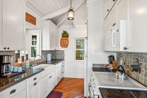 a kitchen with white cabinets and a sink at Hale Moana in Koloa