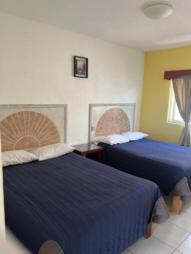 two beds in a hotel room with blue sheets at Hotel Albatros Palace - Bungalow G in Manzanillo