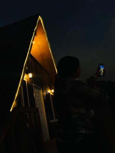 a person taking a picture of a house at night at Cabaña Western Alpine Hn in Santa Bárbara