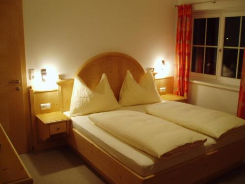 ヴェステンドルフにあるAppartmenthaus Aschaberのベッドルーム1室(大型ベッド1台、木製ヘッドボード付)