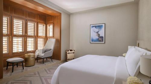 a bedroom with a large white bed and two chairs at Jumeirah Jabal Omar Makkah in Makkah