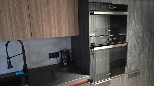 a kitchen with a stove and a microwave at Apartament Dark Prestige NEW ! - dostęp 24h, PROJEKTOR , garaż podziemny , klimatyzacja , duży taras in Kielce