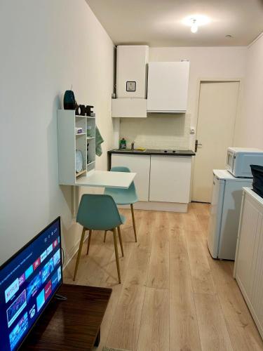 a kitchen with white cabinets and a table and a television at L'étincelant, Centré - Connecté - Lumineux & Cosy in Nancy