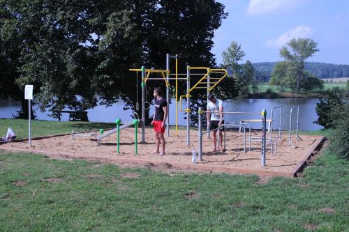 two children playing on a playground next to a lake at Camp Telč - U Roštěnky in Telč