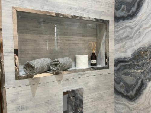 un bagno con uno scaffale con asciugamani e una bottiglia di vino di Sapphire Apartment a Baku
