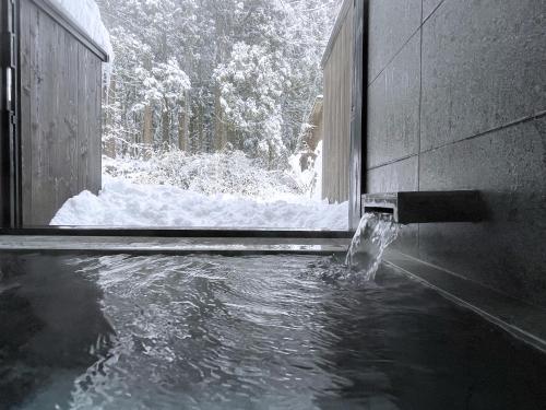 a stream of water coming out of a window with snow at SOMA RESIDENCE HAKUBA in Hakuba