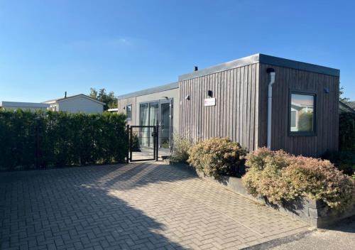 a house with a gate and a brick driveway at Chaletparc Krabbenkreek Zeeland - Chalet 78 in Sint Annaland