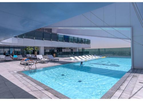 a large swimming pool with chairs and a building at Luxury 2BR Close to Sheikh Zayed Rd, Prime Location, Burj View Opposite Metro in Dubai