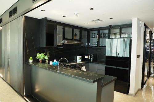 a kitchen with black cabinets and a sink at Luxury 2BR Close to Sheikh Zayed Rd, Prime Location, Burj View Opposite Metro in Dubai
