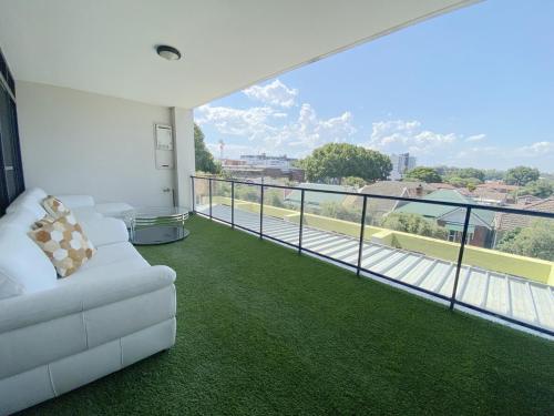 a living room with a white couch on a balcony at 2BR Apartment in Rockdale Near Airport & Train Station in Sydney
