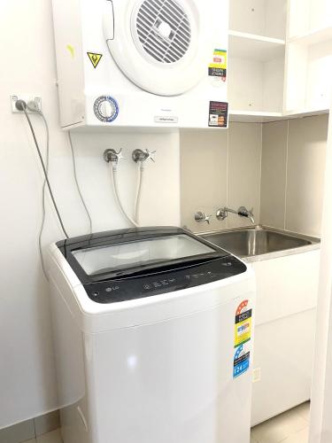 a kitchen with a washing machine and a sink at 2BR Apartment in Rockdale Near Airport & Train Station in Sydney