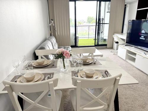 einen weißen Esstisch mit Stühlen und einem TV in der Unterkunft A Cozy 2B2B Apartment near Airport & Train Station in Sydney