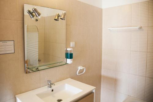 a bathroom with a sink and a shower with a mirror at Sintra Sol - Apartamentos Turisticos in Sintra