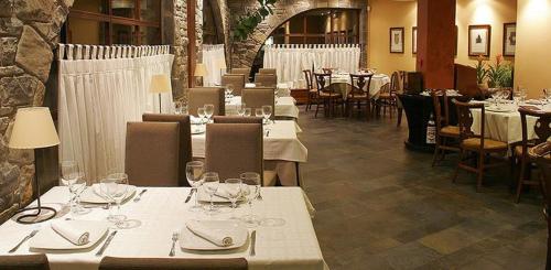 uma sala de jantar com mesas e cadeiras com roupa de mesa branca em Apartamentos Casbas em Sorripas