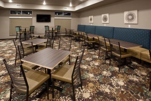 ein Esszimmer mit Tischen und Stühlen auf einem Teppich in der Unterkunft GrandStay Hotel & Suites Valley City in Valley City