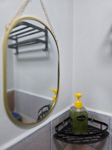 a bottle of green detergent sitting on a shelf next to a mirror at 104 Peaceful and Cosy apartment with cool fan near BTS with free WiFi in Bangkok