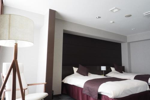 a bedroom with two beds and a black headboard at Kokuminshukusha Shodoshima in Shodoshima